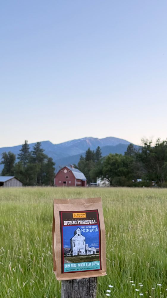 A Big Creek Coffee bag on a fence post, red barn and mountains behind