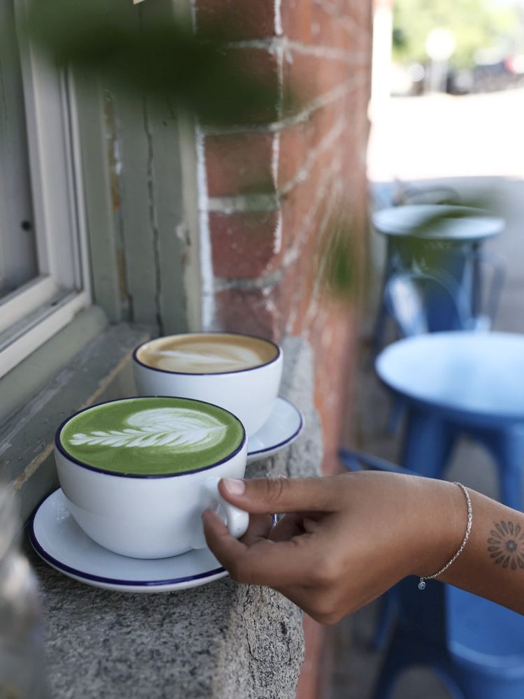 A matcha and a latte on a brick windowsill